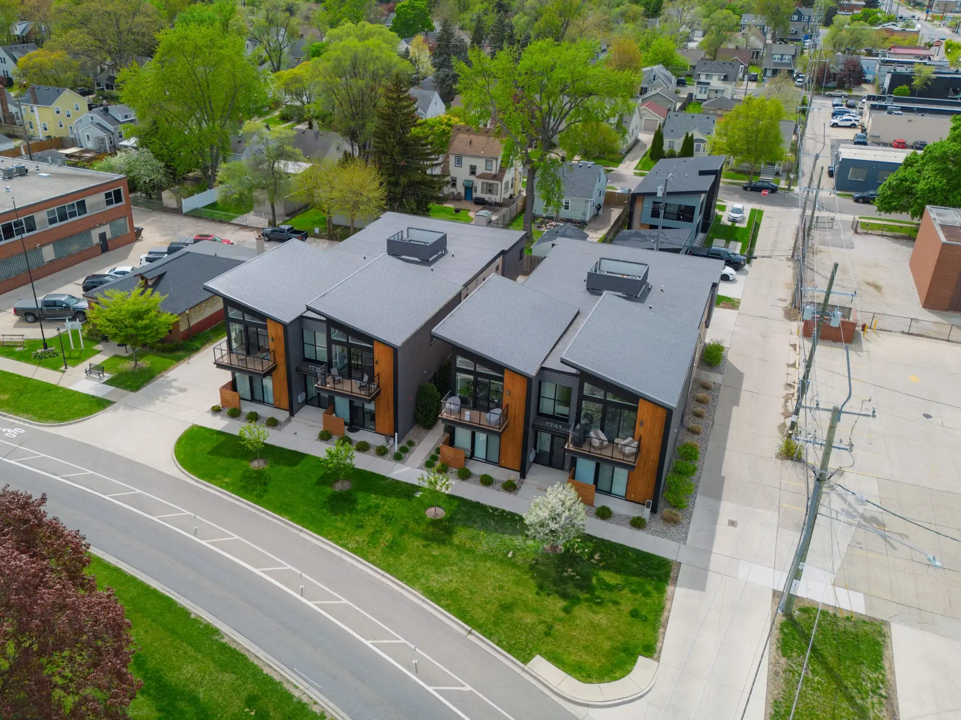 Elevated drone shot showcasing the townhome complex in context with surrounding residential streets, commercial buildings, and tree-lined blocks in Ferndale.