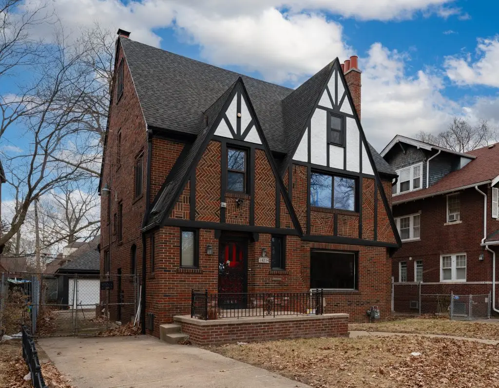 Brick Tudor Revival home with decorative half-timbering, steep gabled rooflines, and a bold red door in Detroit’s University District.