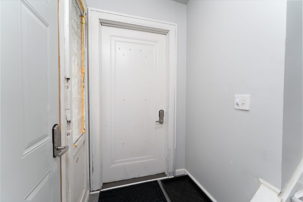 Private entry vestibule at a Detroit short-term rental with coded door locks, gray walls, and separate interior doorways.