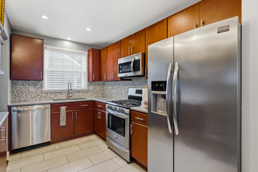 Royal Oak kitchen with warm wood cabinets, stainless steel appliances, mosaic backsplash, and tile flooring.