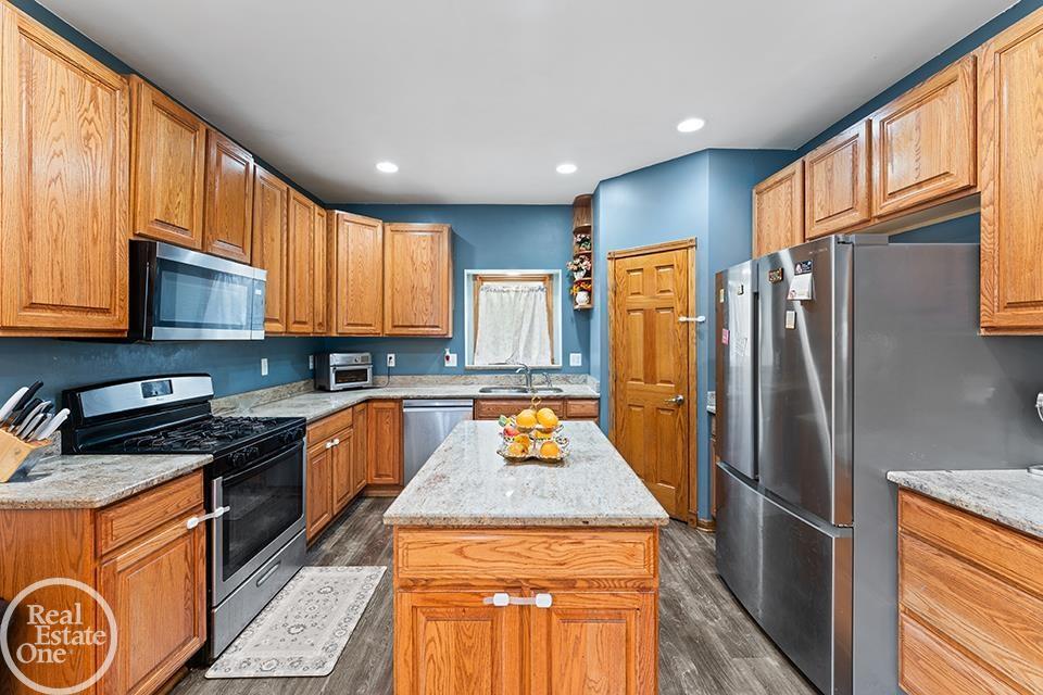 Kitchen at 22212 Mylls Ct in St. Clair Shores with wood cabinets, stainless appliances, island, and blue walls.