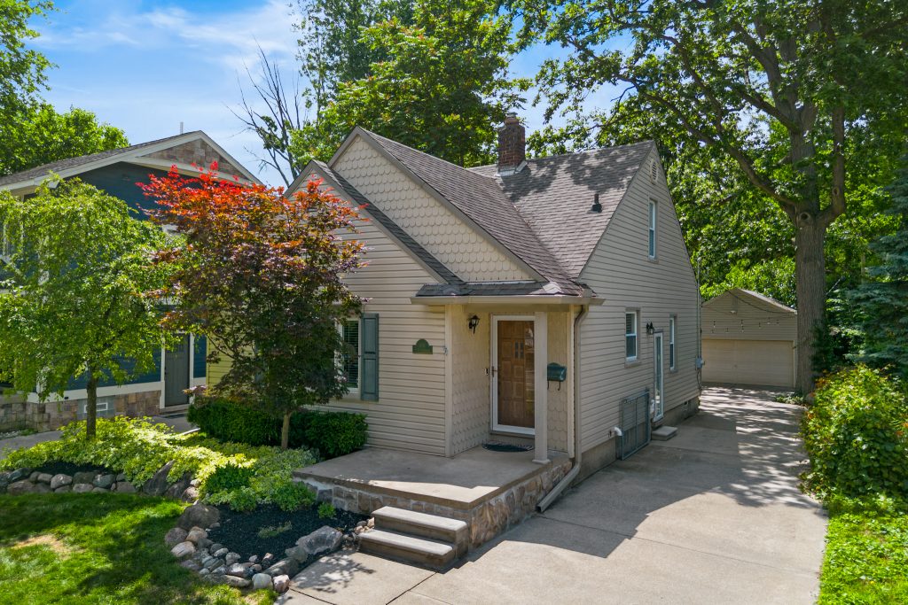 Angled front exterior of a Royal Oak home showing the entry, layered roofline, driveway, and detached garage.