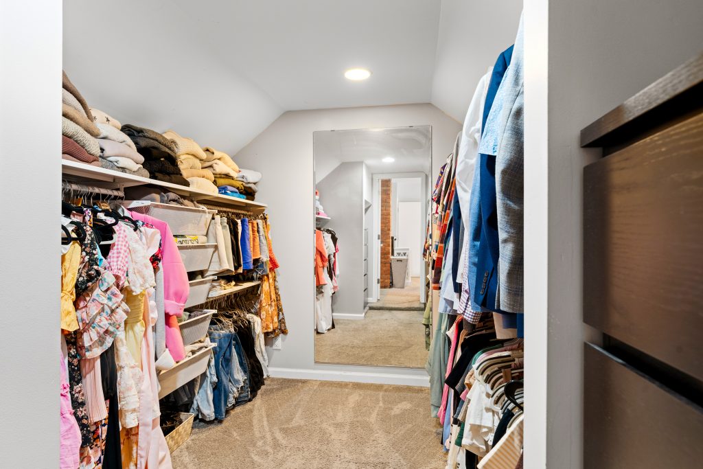 Large walk-in wardrobe closet in a Royal Oak home with hanging clothes, shelving, mirror, and carpet.