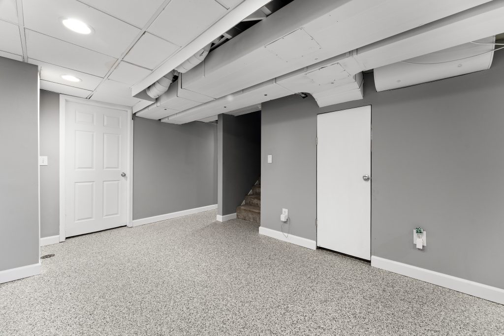 Finished basement recreation room in a Royal Oak home with carpet, gray walls, exposed ceiling elements, and recessed lighting.