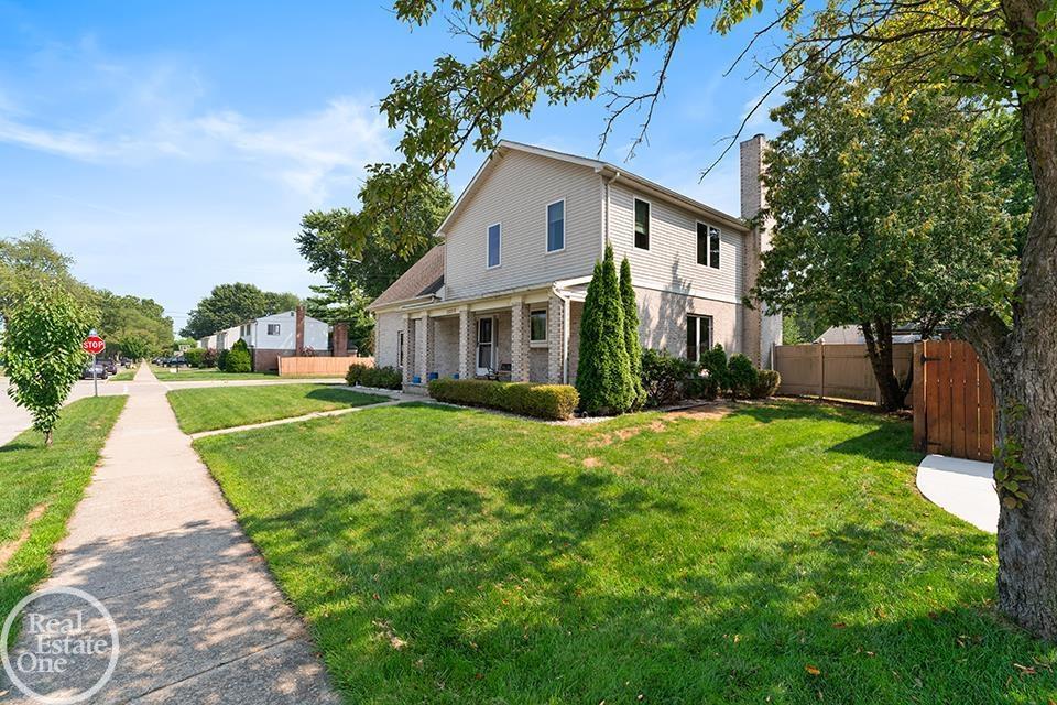 Side exterior view of 22212 Mylls Ct in St. Clair Shores showing corner lot, front lawn, mature trees, sidewalk, and neighborhood street.