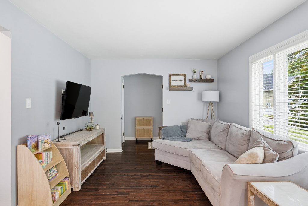 Royal Oak living room with sectional sofa, hardwood floors, large window, and sightline toward the rear of the home.