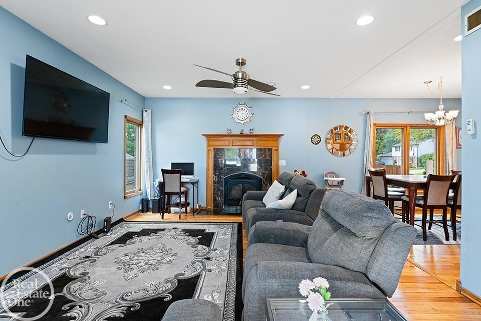 Living room at 22212 Mylls Ct in St. Clair Shores with blue walls, hardwood floors, fireplace, and dining area.