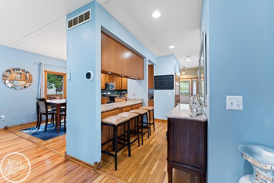 Interior view of 22212 Mylls Ct in St. Clair Shores showing dining area, kitchen breakfast bar, blue walls, wood floors, and entry hallway.