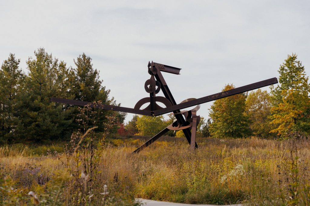 A frontal view of Mark di Suvero's Scarlatti reveals intersecting steel beams, circular elements, and diagonal supports.
